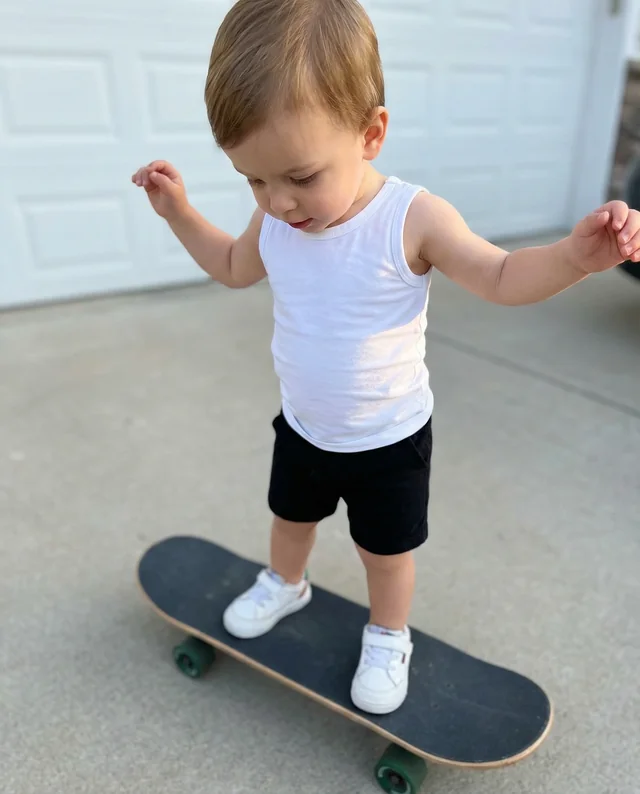 Confident Child on Skateboard in Snug White Tank Top